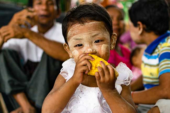 Little girl eating corn