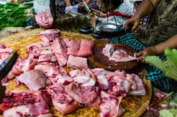 Woman chopping up meat in Bagan market.