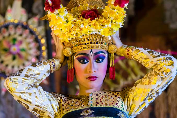 Legong dancer putting on head piece.