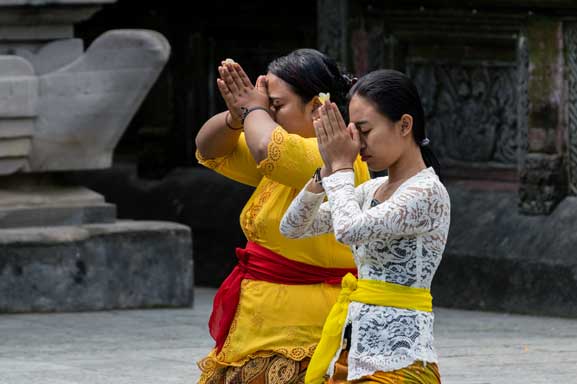 Two women praying at a Hindu temple.