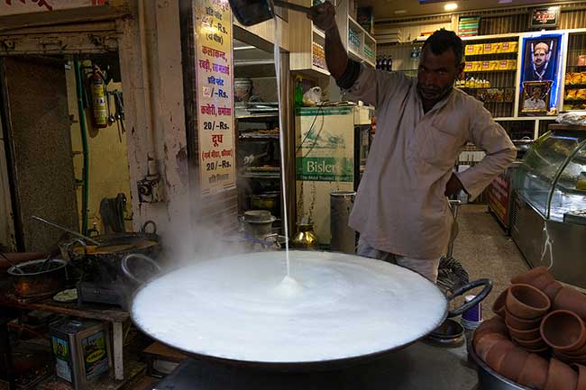 Man stirring large pot of cream.