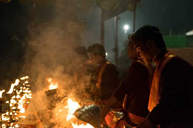 Row of hindu priests in front of candlabras.