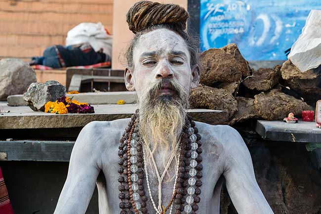 Wide angle of Hindu priests holding candlabras.