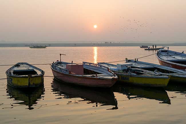 Row of boats under rising sun.